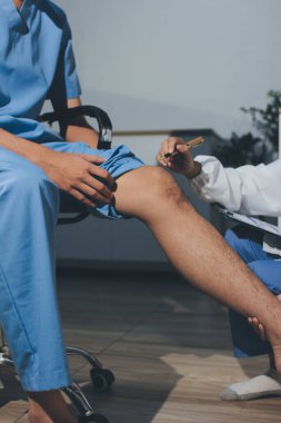 Fizyoterapist hastaya diz ağrısı için egzersiz yapmayı öğretiyor.