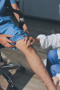 Fizyoterapist hastaya diz ağrısı için egzersiz yapmayı öğretiyor.