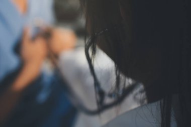 Bir doktor klinik randevusu sırasında hastanın kalbini incelemek için steteskop kullanır..