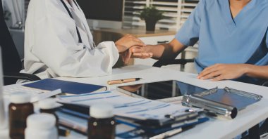 Doktor hastayı kontrol etmeye geldi ve cesaretlendirmek için elini sıktı. Hastanede tedavi edilenleri ve hastaları teselli etmek..