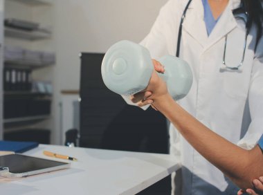 Hemşirenin desteğiyle el ağırlığı kullanan kişi