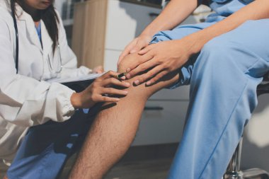 Fizyoterapist hastaya diz ağrısı için egzersiz yapmayı öğretiyor.