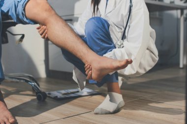 Fizyoterapist hastaya diz ağrısı için egzersiz yapmayı öğretiyor.