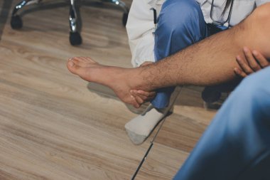 Fizyoterapist hastaya diz ağrısı için egzersiz yapmayı öğretiyor.