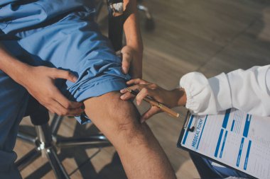 Fizyoterapist hastaya diz ağrısı için egzersiz yapmayı öğretiyor.