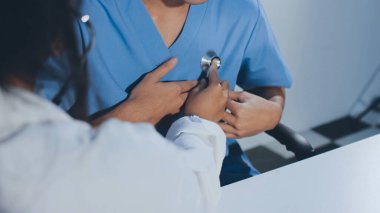 Bir doktor klinik randevusu sırasında hastanın kalbini incelemek için steteskop kullanır..