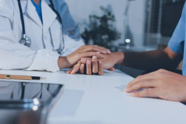 Doktor hastayı kontrol etmeye geldi ve cesaretlendirmek için elini sıktı. Hastanede tedavi edilenleri ve hastaları teselli etmek..