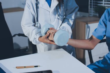 Hemşirenin desteğiyle el ağırlığı kullanan kişi