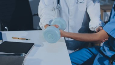 Hemşirenin desteğiyle el ağırlığı kullanan kişi