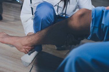 Fizyoterapist hastaya diz ağrısı için egzersiz yapmayı öğretiyor.