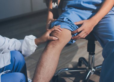 Fizyoterapist hastaya diz ağrısı için egzersiz yapmayı öğretiyor.