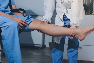 Fizyoterapist hastaya diz ağrısı için egzersiz yapmayı öğretiyor.