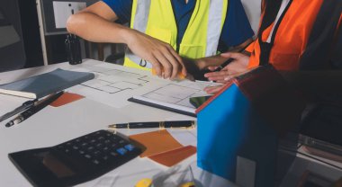 Endüstriyel mühendislerden oluşan bir ekip, fabrikadaki masada bulunan makine planlarını analiz ediyor. Fabrikada ya da üretim tesisinde çalışıyorum..
