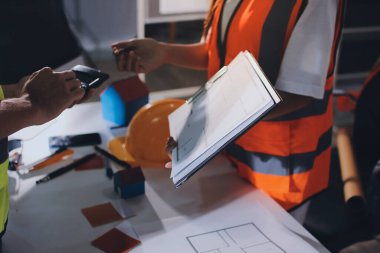 Endüstriyel mühendislerden oluşan bir ekip, fabrikadaki masada bulunan makine planlarını analiz ediyor. Fabrikada ya da üretim tesisinde çalışıyorum..