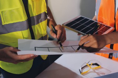 Endüstriyel mühendislerden oluşan bir ekip, fabrikadaki masada bulunan makine planlarını analiz ediyor. Fabrikada ya da üretim tesisinde çalışıyorum..