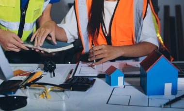 Endüstriyel mühendislerden oluşan bir ekip, fabrikadaki masada bulunan makine planlarını analiz ediyor. Fabrikada ya da üretim tesisinde çalışıyorum..