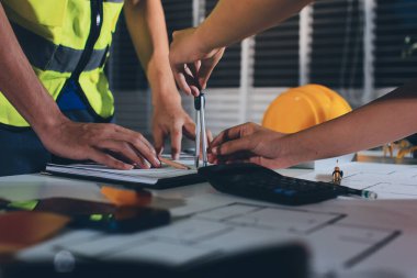 Endüstriyel mühendislerden oluşan bir ekip, fabrikadaki masada bulunan makine planlarını analiz ediyor. Fabrikada ya da üretim tesisinde çalışıyorum..