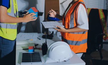 Endüstriyel mühendislerden oluşan bir ekip, fabrikadaki masada bulunan makine planlarını analiz ediyor. Fabrikada ya da üretim tesisinde çalışıyorum..