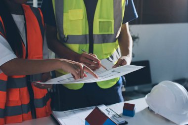 Endüstriyel mühendislerden oluşan bir ekip, fabrikadaki masada bulunan makine planlarını analiz ediyor. Fabrikada ya da üretim tesisinde çalışıyorum..