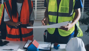 Endüstriyel mühendislerden oluşan bir ekip, fabrikadaki masada bulunan makine planlarını analiz ediyor. Fabrikada ya da üretim tesisinde çalışıyorum..