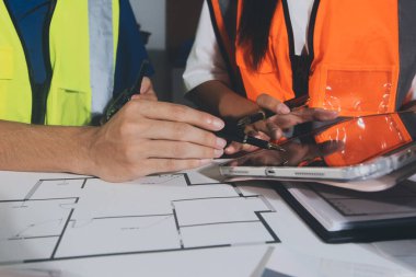 Endüstriyel mühendislerden oluşan bir ekip, fabrikadaki masada bulunan makine planlarını analiz ediyor. Fabrikada ya da üretim tesisinde çalışıyorum..