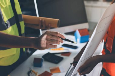 Endüstriyel mühendislerden oluşan bir ekip, fabrikadaki masada bulunan makine planlarını analiz ediyor. Fabrikada ya da üretim tesisinde çalışıyorum..