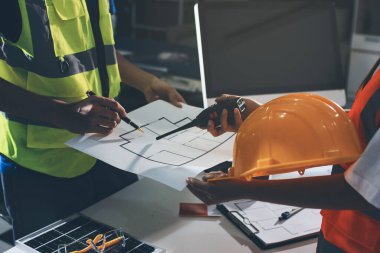 Endüstriyel mühendislerden oluşan bir ekip, fabrikadaki masada bulunan makine planlarını analiz ediyor. Fabrikada ya da üretim tesisinde çalışıyorum..