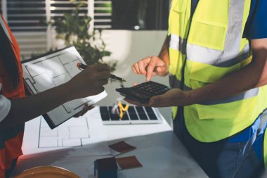 Endüstriyel mühendislerden oluşan bir ekip, fabrikadaki masada bulunan makine planlarını analiz ediyor. Fabrikada ya da üretim tesisinde çalışıyorum..