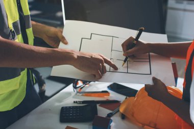 Endüstriyel mühendislerden oluşan bir ekip, fabrikadaki masada bulunan makine planlarını analiz ediyor. Fabrikada ya da üretim tesisinde çalışıyorum..