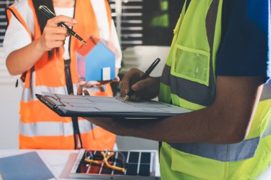 Endüstriyel mühendislerden oluşan bir ekip, fabrikadaki masada bulunan makine planlarını analiz ediyor. Fabrikada ya da üretim tesisinde çalışıyorum..