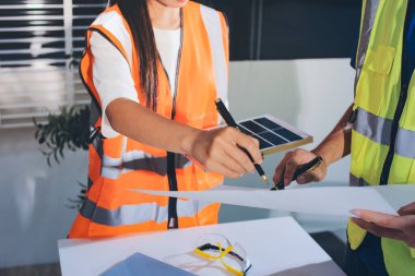 Endüstriyel mühendislerden oluşan bir ekip, fabrikadaki masada bulunan makine planlarını analiz ediyor. Fabrikada ya da üretim tesisinde çalışıyorum..