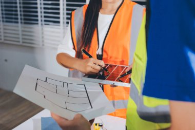 Endüstriyel mühendislerden oluşan bir ekip, fabrikadaki masada bulunan makine planlarını analiz ediyor. Fabrikada ya da üretim tesisinde çalışıyorum..