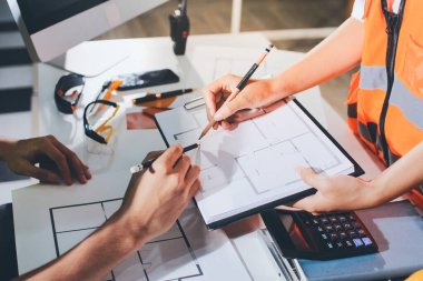 Endüstriyel mühendislerden oluşan bir ekip, fabrikadaki masada bulunan makine planlarını analiz ediyor. Fabrikada ya da üretim tesisinde çalışıyorum..