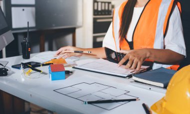 Endüstriyel mühendislerden oluşan bir ekip, fabrikadaki masada bulunan makine planlarını analiz ediyor. Fabrikada ya da üretim tesisinde çalışıyorum..