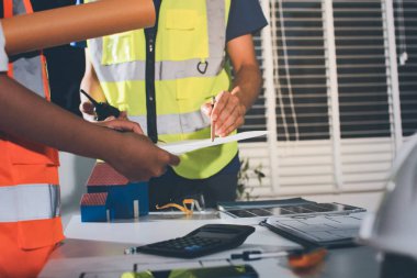 Endüstriyel mühendislerden oluşan bir ekip, fabrikadaki masada bulunan makine planlarını analiz ediyor. Fabrikada ya da üretim tesisinde çalışıyorum..