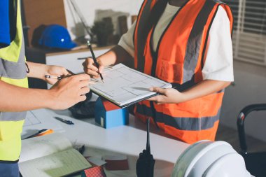 Endüstriyel mühendislerden oluşan bir ekip, fabrikadaki masada bulunan makine planlarını analiz ediyor. Fabrikada ya da üretim tesisinde çalışıyorum..