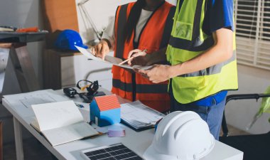 Endüstriyel mühendislerden oluşan bir ekip, fabrikadaki masada bulunan makine planlarını analiz ediyor. Fabrikada ya da üretim tesisinde çalışıyorum..