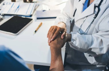 Doktor hastayı kontrol etmeye geldi ve cesaretlendirmek için elini sıktı. Hastanede tedavi edilenleri ve hastaları teselli etmek..