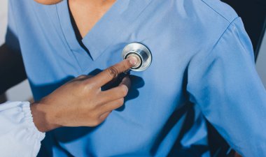 Bir doktor klinik randevusu sırasında hastanın kalbini incelemek için steteskop kullanır..