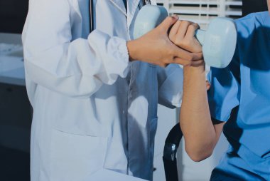 Hemşirenin desteğiyle el ağırlığı kullanan kişi