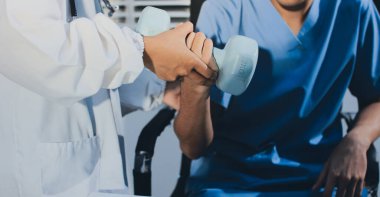 Hemşirenin desteğiyle el ağırlığı kullanan kişi