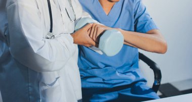 Hemşirenin desteğiyle el ağırlığı kullanan kişi