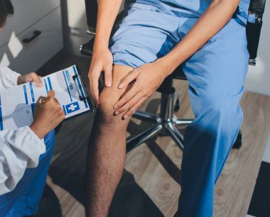 Fizyoterapist hastaya diz ağrısı için egzersiz yapmayı öğretiyor.