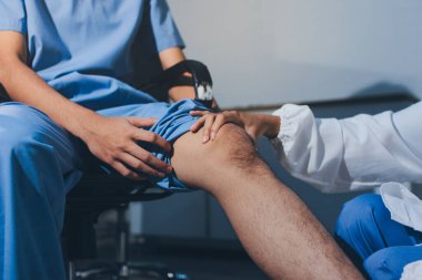 Fizyoterapist hastaya diz ağrısı için egzersiz yapmayı öğretiyor.