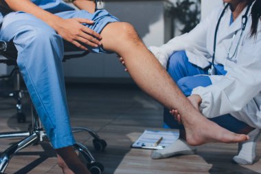 Fizyoterapist hastaya diz ağrısı için egzersiz yapmayı öğretiyor.