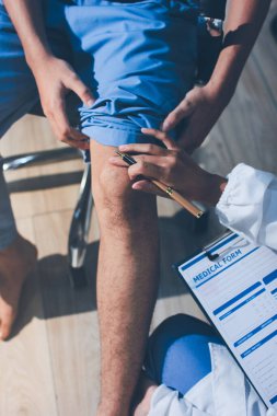 Fizyoterapist hastaya diz ağrısı için egzersiz yapmayı öğretiyor.