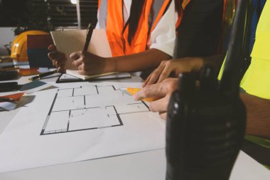 Endüstriyel mühendislerden oluşan bir ekip, fabrikadaki masada bulunan makine planlarını analiz ediyor. Fabrikada ya da üretim tesisinde çalışıyorum..