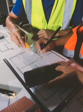 Endüstriyel mühendislerden oluşan bir ekip, fabrikadaki masada bulunan makine planlarını analiz ediyor. Fabrikada ya da üretim tesisinde çalışıyorum..