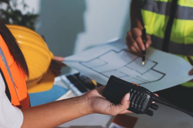 Endüstriyel mühendislerden oluşan bir ekip, fabrikadaki masada bulunan makine planlarını analiz ediyor. Fabrikada ya da üretim tesisinde çalışıyorum..