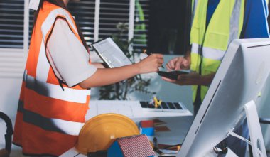 Endüstriyel mühendislerden oluşan bir ekip, fabrikadaki masada bulunan makine planlarını analiz ediyor. Fabrikada ya da üretim tesisinde çalışıyorum..